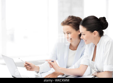 two smiling businesswomen working with laptop in office Stock Photo