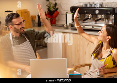 Feeling extremely happy. Cheerful beaming husband and wife feeling extremely happy after opening cafe Stock Photo