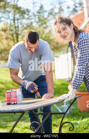 Young couple doing home improvement in the garden while priming and painting a table Stock Photo