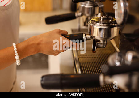 Female barista. Close up of female barista wearing bracelet making coffee for clients in the morning Stock Photo