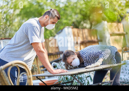 Young couple wearing a respirator while painting and renovating the garden furniture in the garden Stock Photo