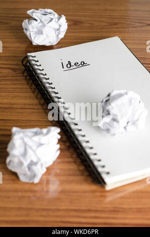 notebook write idea word with crumpled on wooden background Stock Photo