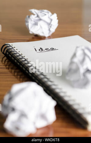 notebook write idea word with crumpled on wooden background Stock Photo