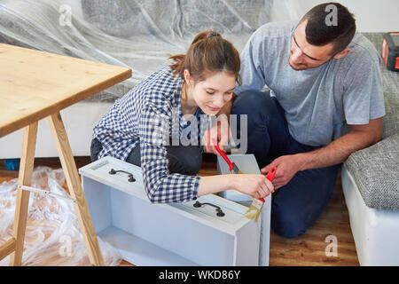 Young couple as a handyman renovating and painting drawers in their new home Stock Photo