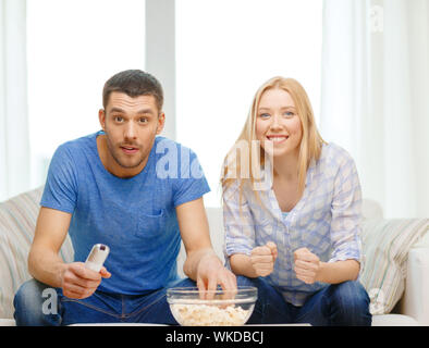 smiling couple with popcorn cheering sports team Stock Photo