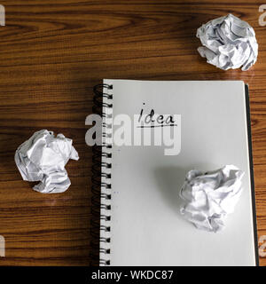 notebook write idea word with crumpled on wooden background Stock Photo