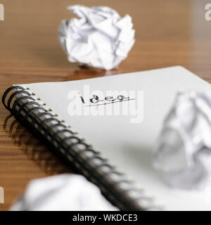 notebook write idea word with crumpled on wooden background Stock Photo