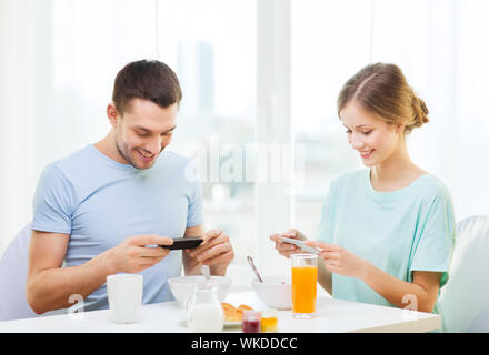 smiling couple with smartphones taking picture Stock Photo