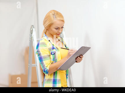 repair, building and home concept - smiling woman with clipboard Stock Photo