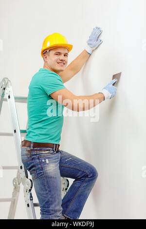 repair, renovation and home concept - smiling man in helmet doing renovations at home Stock Photo