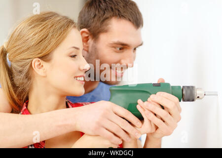 repair, interior design, building, renovation and home concept - smiling couple drilling hole in wall at home Stock Photo