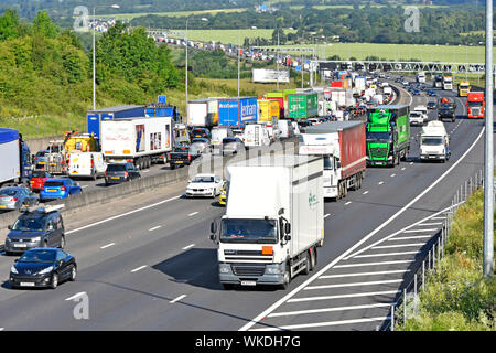 View from above of motorway countryside landscape with traffic jam on M25 & busy lorry truck movement on near side four lane section Essex England UK Stock Photo