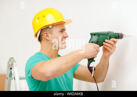 man with electric drill making hole in wall Stock Photo