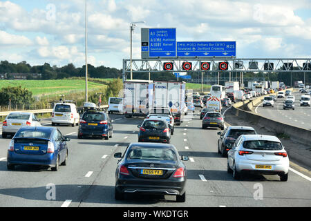 Traffic M25 motorway bend & blue route road sign overhead gantry electronic variable speed signs set at 40 MPH Friday PM rush hour London England UK Stock Photo