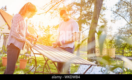 Couple painted table in the garden together as a home improvement work in summer Stock Photo