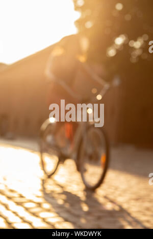 young woman in hat move on bike at old european street, blurred image Stock Photo
