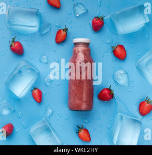 Berry smoothie in glass bottle on blue background with ice Stock Photo