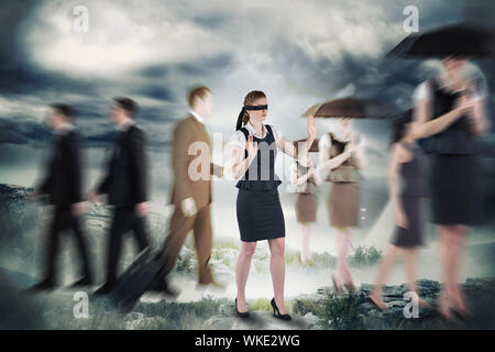 Redhead businesswoman in a blindfold against stormy sky with tornado over landscape Stock Photo