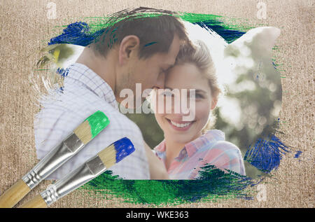 Composite image of happy couple in the countryside against weathered surface with paintbrushes Stock Photo