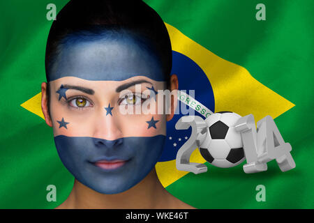Composite image of honduras football fan in face paint against world cup 2014 with brasil flag Stock Photo