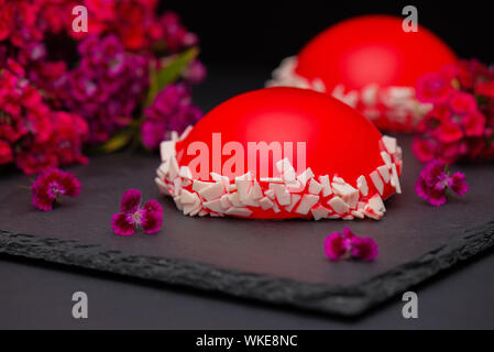 Red strawberry glaze mousse cake, on dark background, closeup. Red cake with mirror glaze. Stock Photo