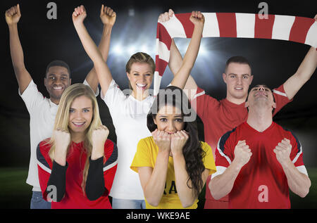 Composite image of various football fans against football pitch under spotlights Stock Photo