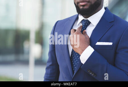 Unrecognizable Afro Man Adjusting Necktie Standing Outdoor In City Stock Photo