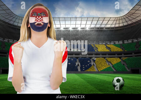 Excited croatia fan in face paint cheering against large football stadium with brasilian fans Stock Photo