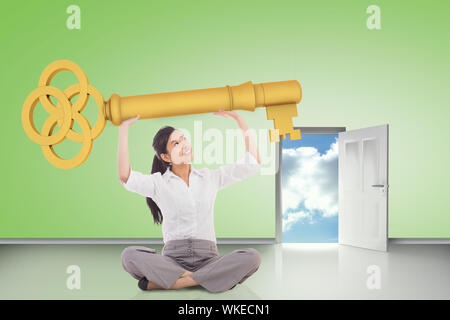 Composite image of businesswoman sitting holding large key against door opening showing blue sky Stock Photo