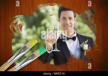 Composite image of groom toasting with champagne with paintbrush dipped in green against wooden oak table Stock Photo