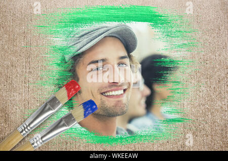Composite image of smiling designer with paintbrush dipped in blue against weathered surface Stock Photo
