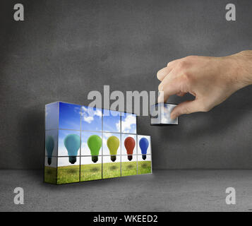 Hand building wall showing five colored light bulb in the air Stock Photo