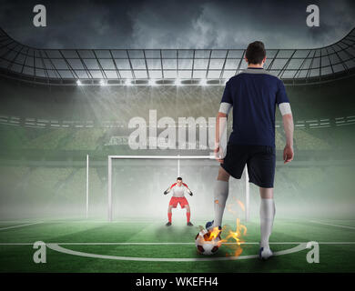 Composite image of football player about to take a penalty against football pitch in large stadium Stock Photo