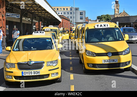Bournemouth railway station taxi rank with two lanes of parked cars as yellow cabs lined up waiting for train passengers summer Dorset England UK Stock Photo