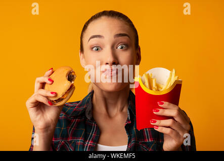 Hungry Girl Eating Fast Food Burger And French-Fries, Studio Shot Stock Photo