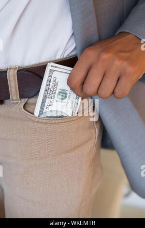 Dodgy businessman pocketing wad of dollars in his office Stock Photo
