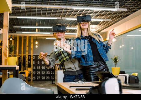 young Caucasian people man and woman wear virtual reality glasses. best friends couple having fun using new technology testing vr goggles connection Stock Photo