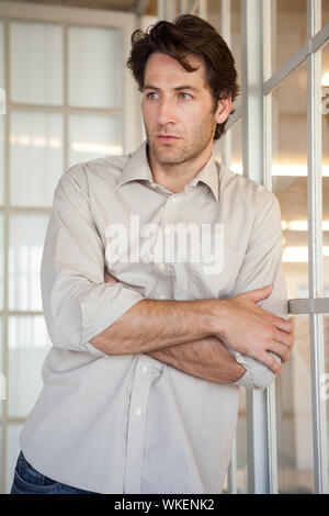 Casual worried businessman leaning on window in his office Stock Photo