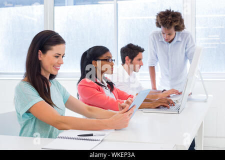 Workers on tablets and laptops in the office Stock Photo