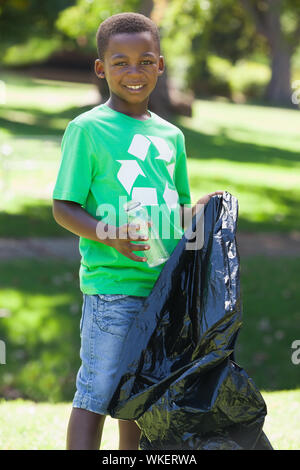 Young boy in recycling tshirt picking up trash on a sunny day Stock Photo