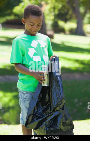 Young boy in recycling tshirt picking up trash on a sunny day Stock Photo