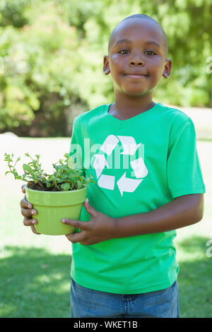 Little boy in recycling tshirt holding potted plant on a sunny day Stock Photo