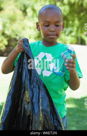 Little boy in recycling tshirt picking up trash on a sunny day Stock Photo