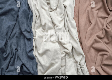 Knitted indigo, beige and brown fabrics, draped jersey cloths background. Stock Photo