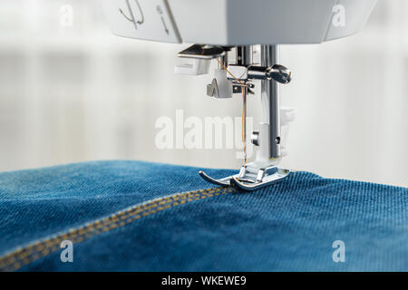 A needle and thread sew up a hole in a denim. Work of a seamstress or  tailor with a needle Stock Photo - Alamy