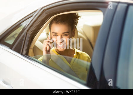 Happy woman sitting in car and talking on phone Stock Photo