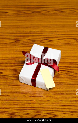 white gift box and red ribbin with tag on wood background Stock Photo