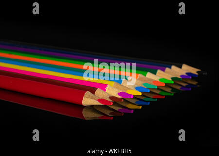 Group of twelve whole colored pencil isolated on black glass Stock Photo