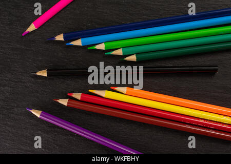 Group of twelve whole colored pencil flatlay on grey stone Stock Photo