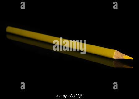 One whole yellow colored pencil isolated on black glass Stock Photo